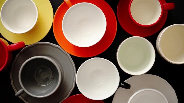 Empty colorful modern ceramic plates and cups collection. Various of dishware over black background. Top view