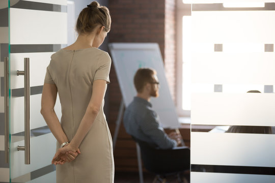 Rear view at nervous woman standing at door waiting focused on speech preparation for important meeting negotiation feeling panic stress or lack of confidence thinking of public speaking fear concept.