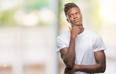 Obraz premium Young african american man over isolated background with hand on chin thinking about question, pensive expression. Smiling with thoughtful face. Doubt concept.