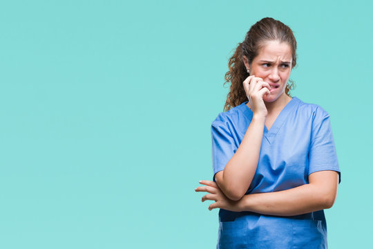 Young brunette doctor girl wearing nurse or surgeon uniform over isolated background looking stressed and nervous with hands on mouth biting nails. Anxiety problem.
