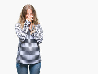 Beautiful young blonde woman wearing stripes sweater over isolated background smelling something stinky and disgusting, intolerable smell, holding breath with fingers on nose. Bad smells concept.