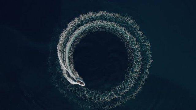 Aerial shot of a fast speedboat going around in the circle and making beautiful circle path in the sea. Top travel destination. Vacation in Croatia