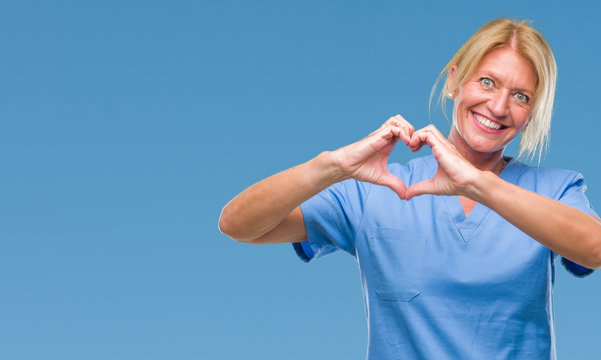 Middle age blonde woman wearing doctor nurse uniform over isolated background smiling in love showing heart symbol and shape with hands. Romantic concept.