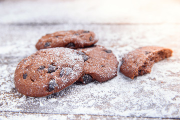 Shortbread cookies with chocolate chips on wooden background sprinkled with powdered sugar. Fresh pastry. Oatmeal cookies for dessert.