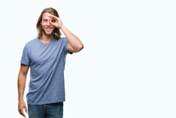 Young handsome man with long hair over isolated background doing ok gesture with hand smiling, eye looking through fingers with happy face.