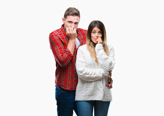 Young couple in love wearing winter sweater over isolated background looking stressed and nervous with hands on mouth biting nails. Anxiety problem.