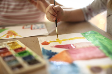 child draws with a brush and paints,blurred