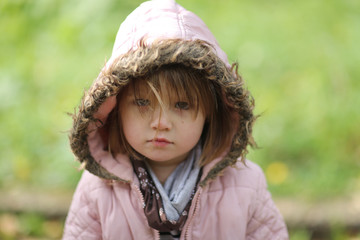 Sad shaggy toddler in jacket with hood, emotions