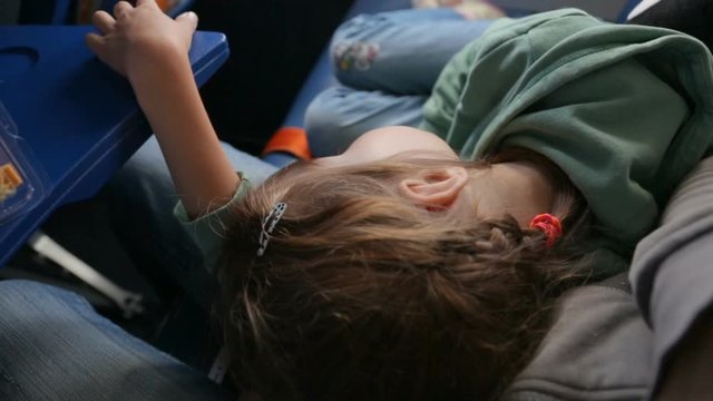 Sleeping little girl in mothers lap in airplane