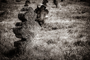 christian cross on an old shattered and cracked grave in an old cemetery in Europe. Image in black and white color style