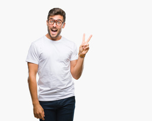Young handsome man wearing glasses over isolated background smiling with happy face winking at the camera doing victory sign. Number two.