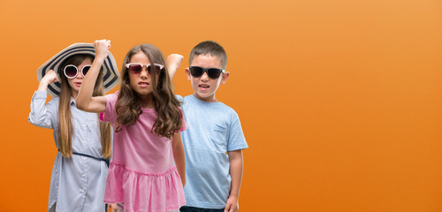 Group of boy and girls kids over orange background annoyed and frustrated shouting with anger, crazy and yelling with raised hand, anger concept