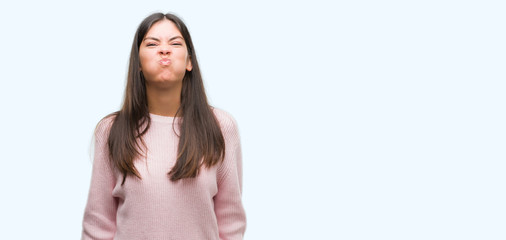 Fototapeta premium Young beautiful hispanic woman wearing a sweater puffing cheeks with funny face. Mouth inflated with air, crazy expression.