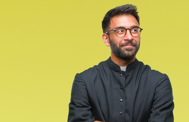 Adult hispanic catholic priest man over isolated background smiling looking side and staring away thinking.