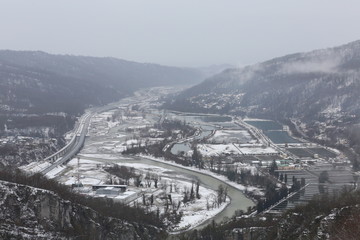 High-mountain, suspended rope bridge, which offers stunning views of the gorge, which runs a mountain river and a view of the village located far away in the valley