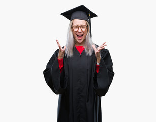 Young blonde woman wearing graduate uniform over isolated background celebrating mad and crazy for success with arms raised and closed eyes screaming excited. Winner concept