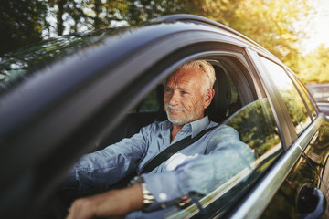 Smiling senior man driving along a country road