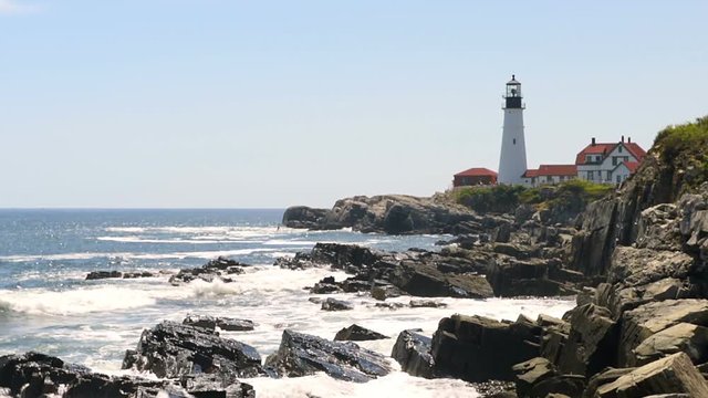 Cliff rocks side view shore with Portland Head Lighthouse in Fort Williams park in Cape Elizabeth, Maine during summer day