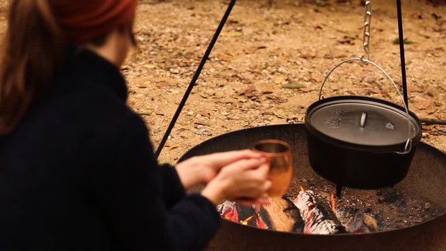 woman with copper mug watching dutch oven cook