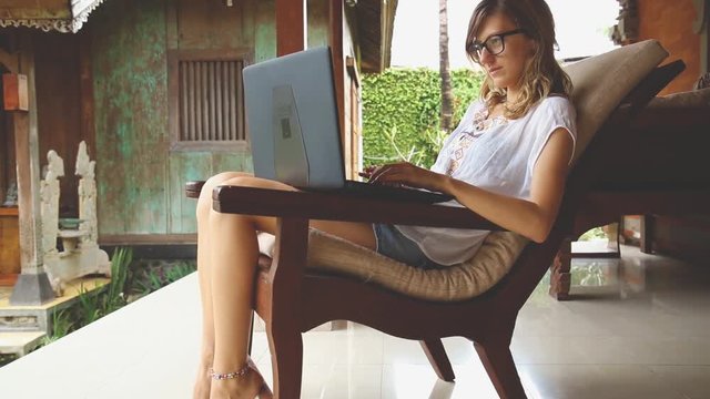 Girl using laptop on the garden porch.