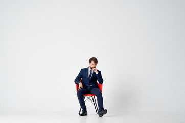 man in a suit sitting on a red chair