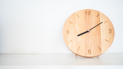 Wooden round wall clock on white shelf