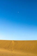 Sand dunes in the Maranjab desert, near Kashan, Iran, at sunset with the moon light visible high in the sky. maranjab desert is one of the main landmarks of the region
