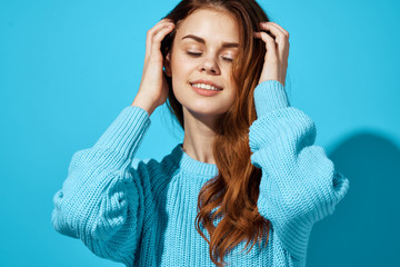 red-haired woman with eyes closed and in a blue sweater