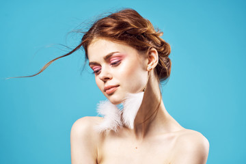 beautiful woman earrings in the form of feathers on a blue background