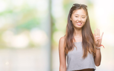 Young asian woman wearing sunglasses over isolated background showing and pointing up with fingers number four while smiling confident and happy.
