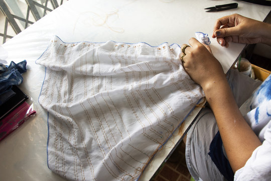 Thai woman people fold bundle and sewing or arashi shibori on fabric at workshop in Nonthaburi, Thailand