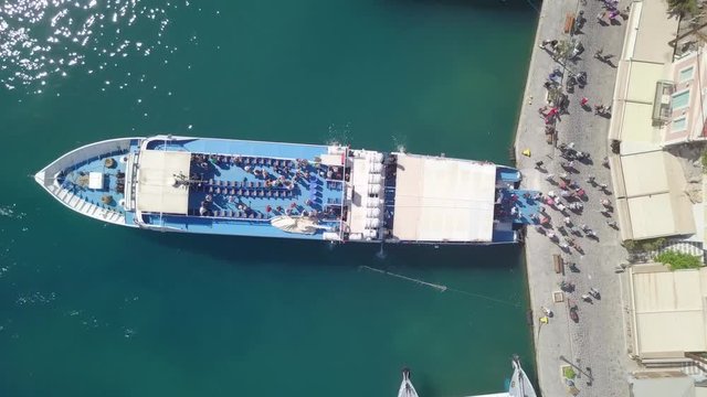 People leaving a medium sized passenger ferry docked at a Greek island port - Top down aerial footage.