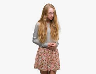 Blonde teenager woman wearing flowers skirt with hand on stomach because nausea, painful disease feeling unwell. Ache concept.