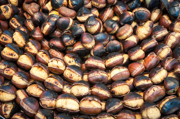 Roasted chestnuts in a frying pan by a street vendor . 
