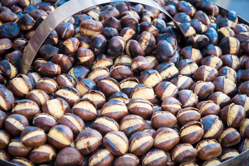 Roasted chestnuts in a frying pan by a street vendor . 