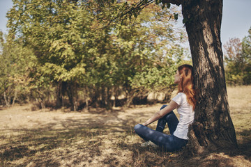 Naklejka premium woman sitting on the ground leaning on a tree