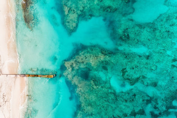 Beach with pier aerial top view. Caribbean ocean water, coral reefs. Summer background