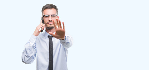 Young business adult man talking on the phone with open hand doing stop sign with serious and...
