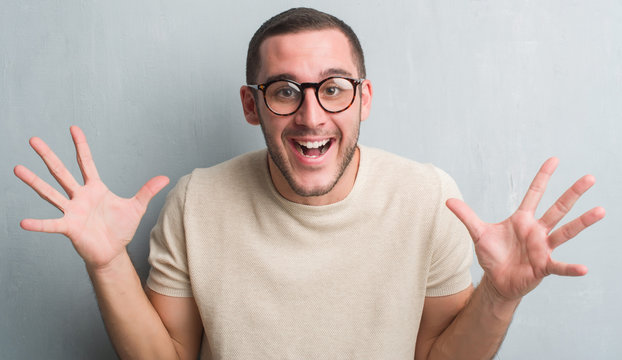 Young caucasian man over grey grunge wall very happy and excited, winner expression celebrating victory screaming with big smile and raised hands