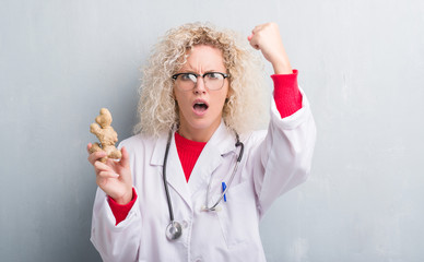 Young blonde dietitian doctor woman over grunge grey wall holding ginger annoyed and frustrated...