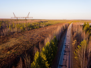 Road through the taiga forest. Oil deposit. Oil production. Sunset on the Vasyugan swamp. Nature landscape from aerial view. Off road transportation. Siberia, Russia.