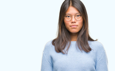 Fototapeta premium Young asian woman wearing winter sweater over isolated background with serious expression on face. Simple and natural looking at the camera.