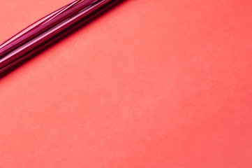 Fototapeta premium A bunch of straight red-painted wood sticks serves as a focal point on a predominantly empty slightly gradient and subtly textured red paper background.