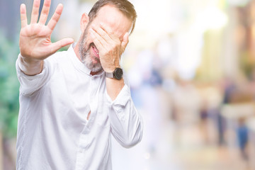 Obraz premium Middle age hoary senior man over isolated background covering eyes with hands and doing stop gesture with sad and fear expression. Embarrassed and negative concept.