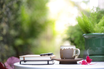 Vintage brown cup with notebook and green plants at outdoor