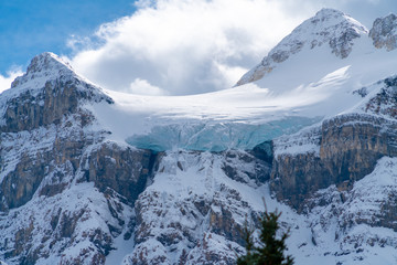 A blue glacier hangs onto a high cliff on a mountain top in Canada