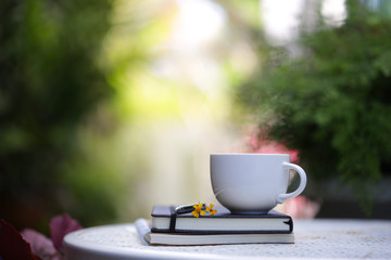 White cup with yellow flowers and notebooks