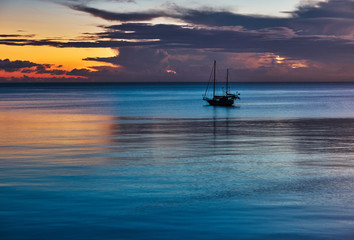 Naklejka na ściany i meble Sail boat in the sea against the background of colourful dawn 