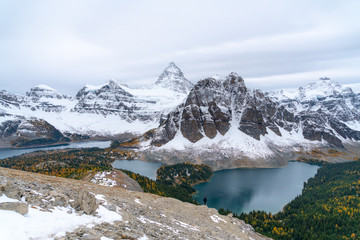 A distant silhouette of a hiker overlooking a blue colored lake in the Canadian Rockies