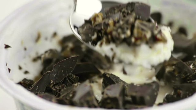 close-up of man use the spoon for eat white yogurt and pieces of brown chocolate, health food diet and nutrition concept